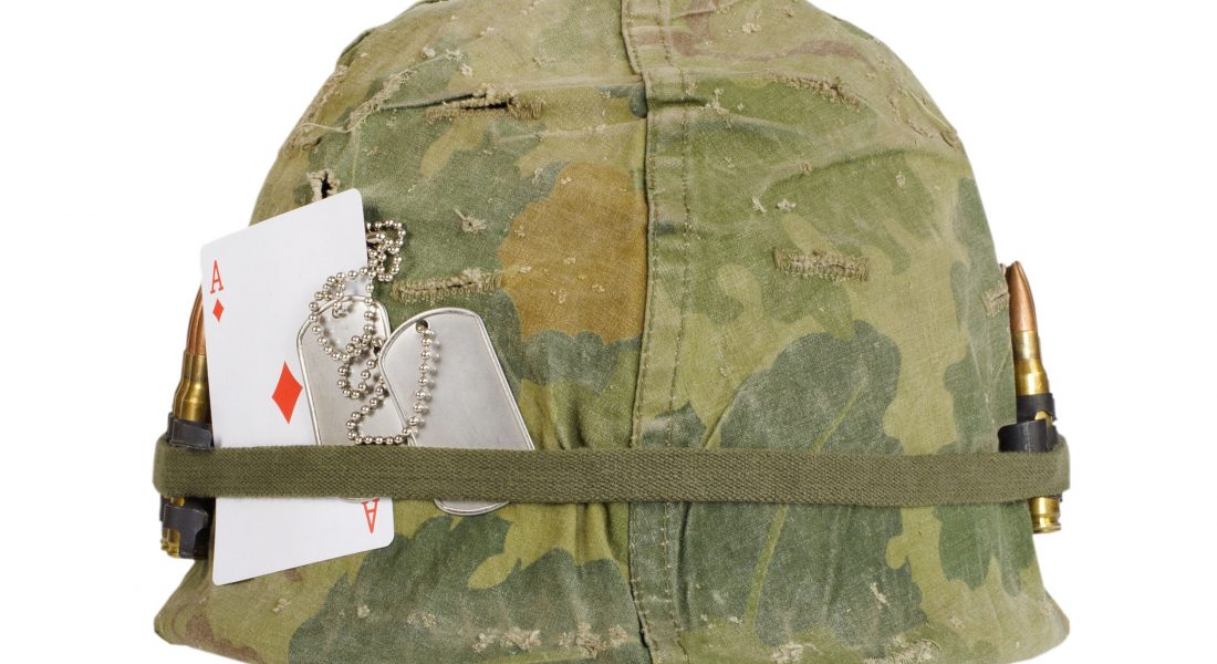 US Army helmet Vietnam war period with camouflage cover and ammo belt, dog tag and amulet - playing card ace of diamonds isolated on white background