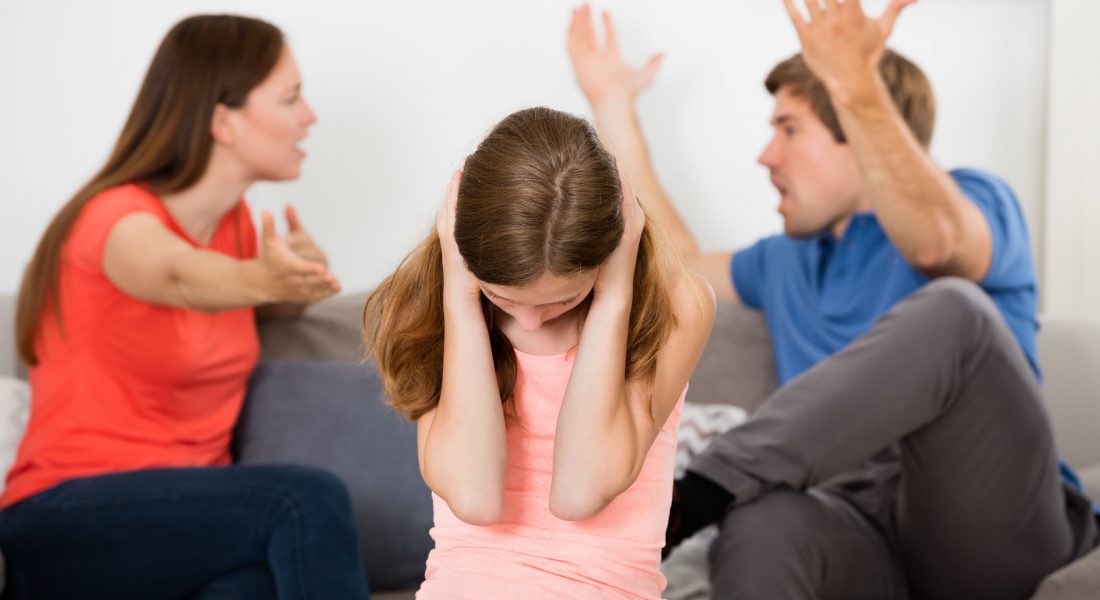 Upset Girl Covering Her Ears In Front Of Parent Having Argument